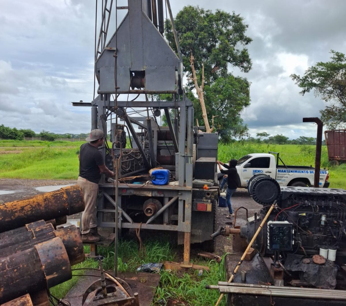 Cuadrilla de Hidroperforaciones trabajando en la torre junto al pickup rotulado Mantenimiento de pozos, en Retalhuleu